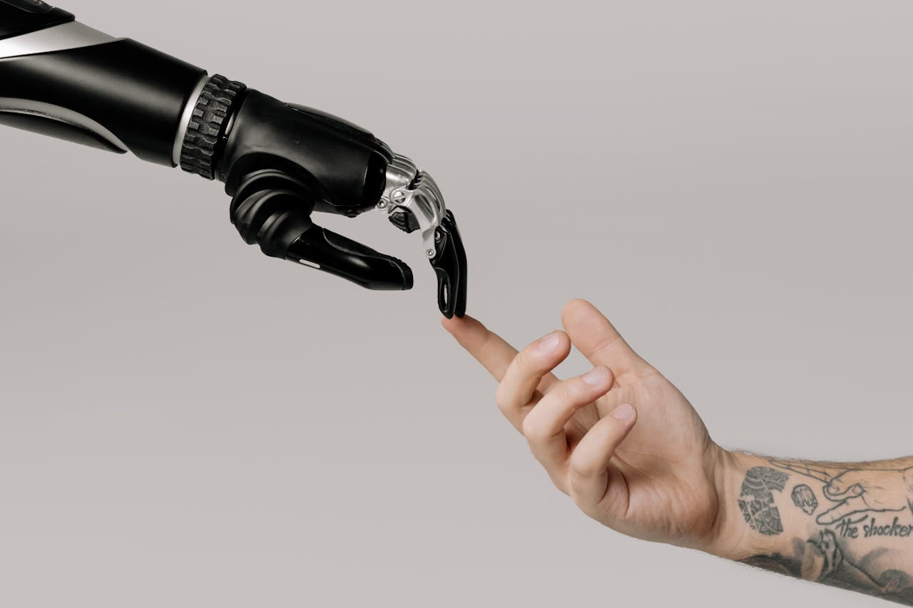 关于我们 A human hand with tattoos reaching out to a robotic hand on a white background.